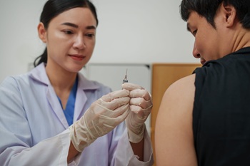 doctor holding syringe and making injection vaccine to male patient