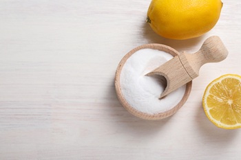 Baking soda and lemons on white wooden table, top view. Space for text