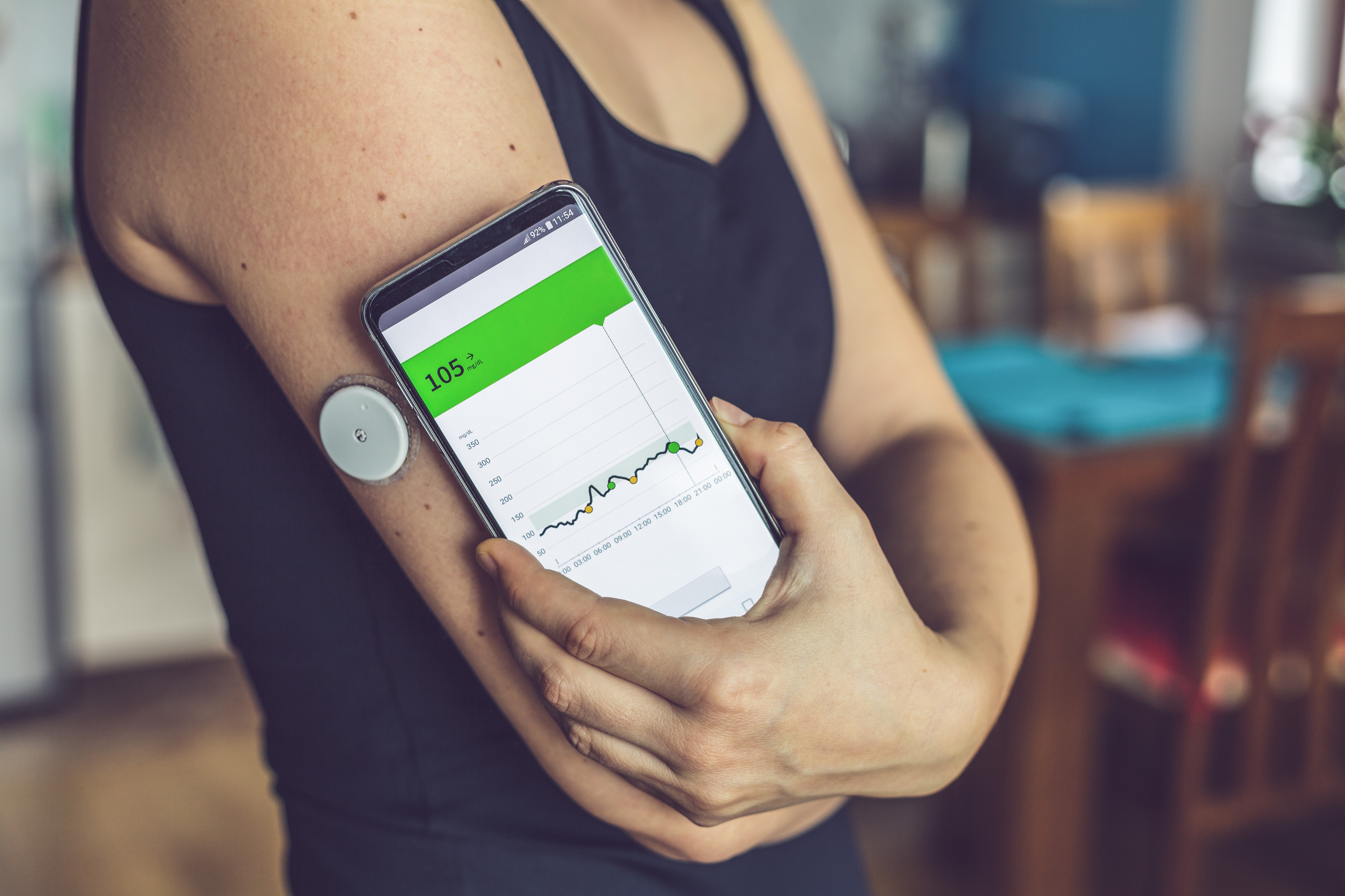 Person reading results from continuing glucose monitor (CGM) device on arm